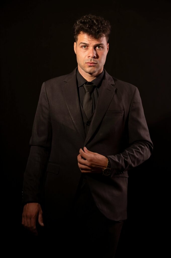 Sophisticated portrait showcasing a man in a stylish dark suit against a black background.